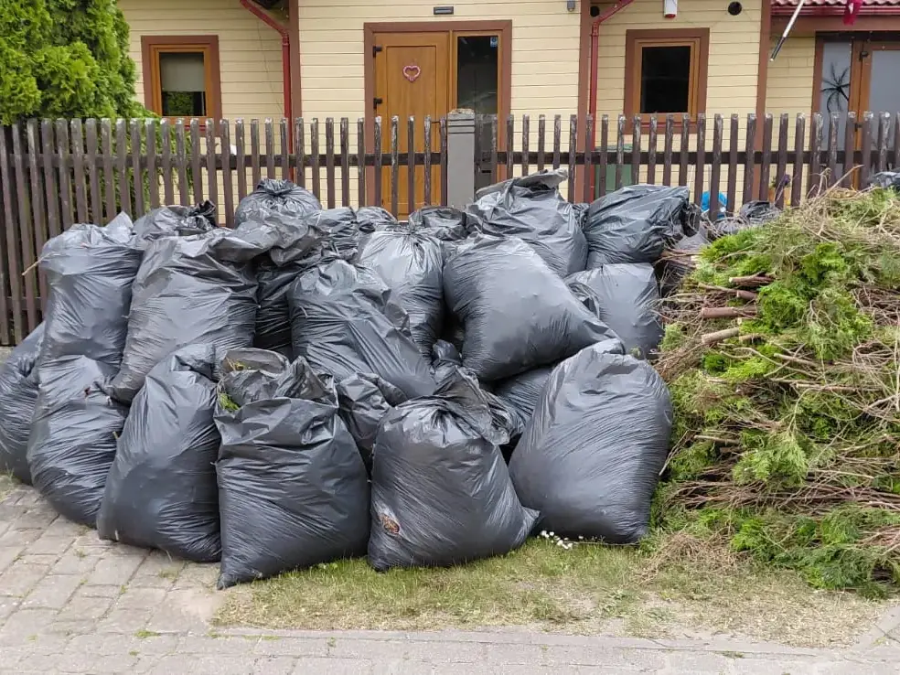 Maisi ar savāktām lapām un zariem pie žoga pēc dārza sakopšanas